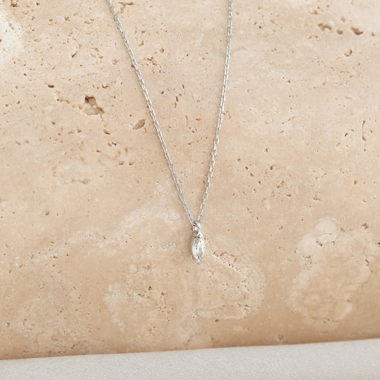 Close-up of a woman wearing a Marquise Diamond Necklace White Gold - Violetta with a delicate pendant on a fine chain