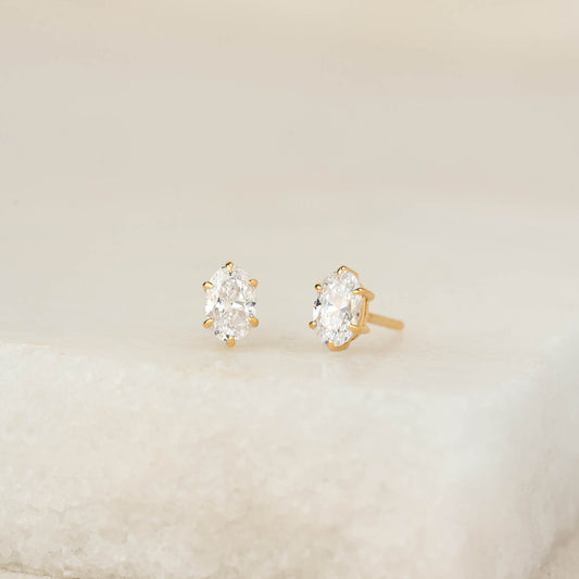 A pair of oval-cut gemstone stud earrings set in Gold Vermeil, displayed on a soft neutral surface with a minimal, elegant background.