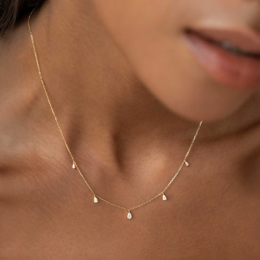 Close-up of woman wearing Pear Cut Diamond Pendant Necklace 14k Gold - Sylvie with five pear cut diamonds on gold chain