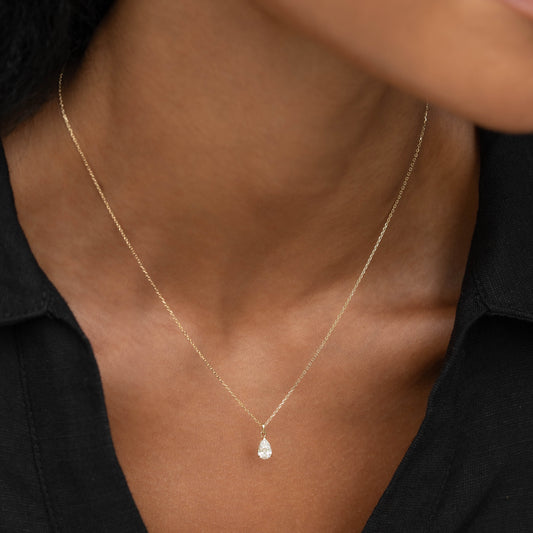 Close-up of a woman wearing Pear Cut Diamond Pendant Necklace 14k Gold - Oline with black top on neutral background