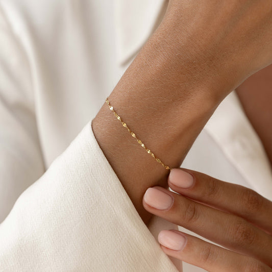 Close-up of a wrist wearing the Petal Chain Bracelet 14k Gold - Florence with petal-shaped links on neutral background