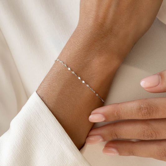 Close-up of a delicate Petal Chain Bracelet White Gold - Florence on a wrist with natural light and neutral background