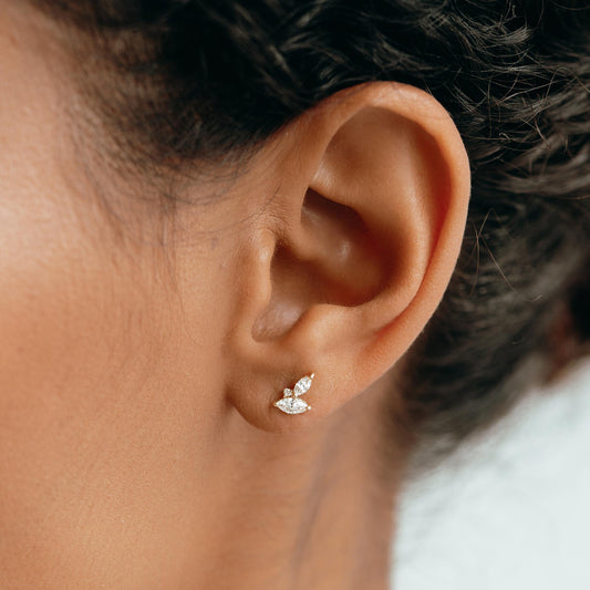Close-up of a woman wearing Diamond Leaf Earrings 14k Gold - Selma with lab grown diamonds on a neutral background