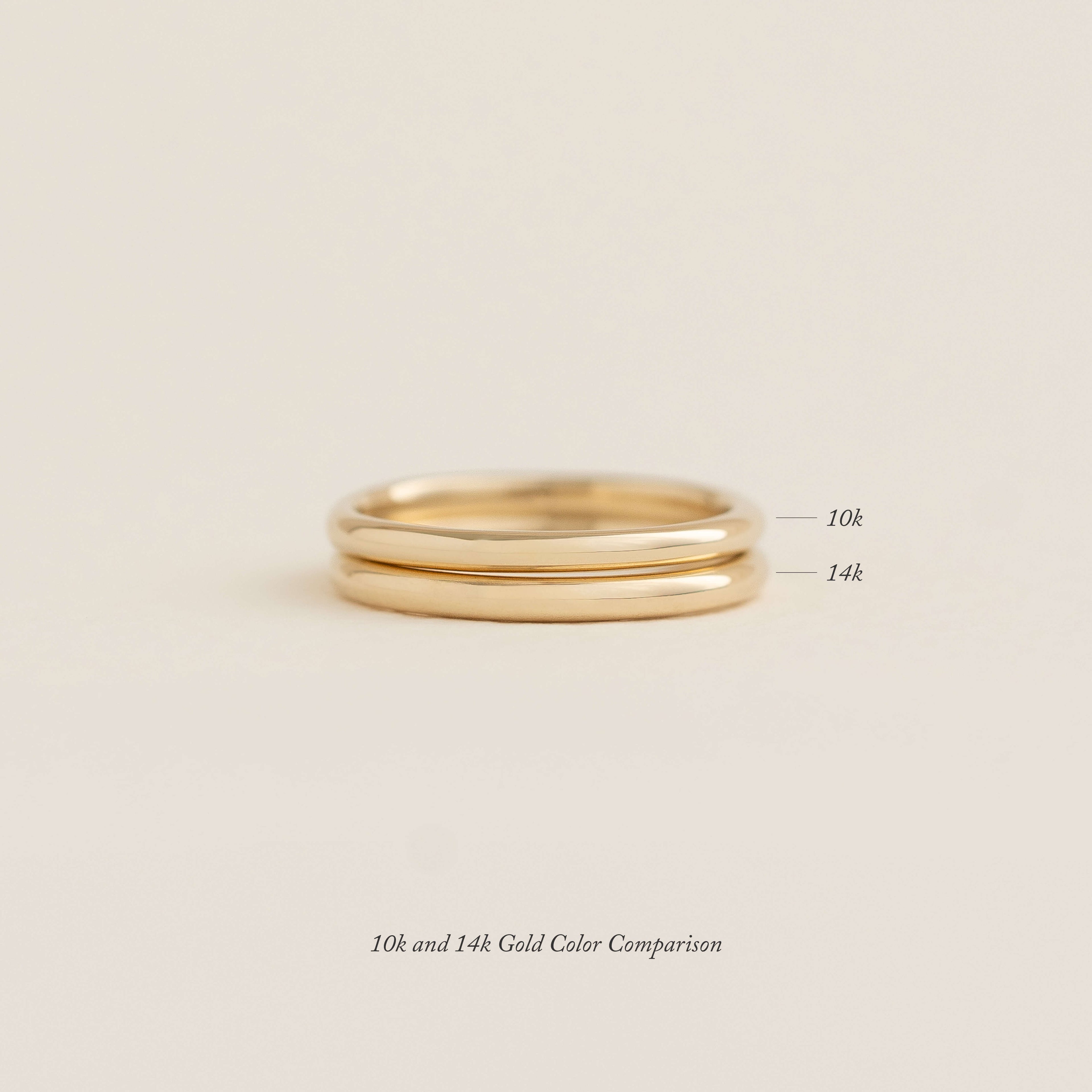 Two gold rings are stacked on a neutral background, labeled as 10k and 14k gold to compare their color. Text below reads "10k and 14k Gold Color Comparison.