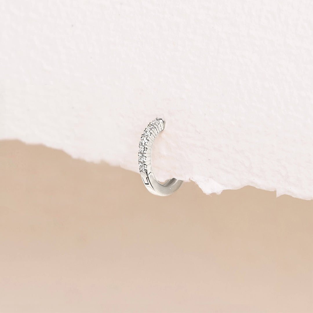 14k White Gold Diamond Huggie Earring - Susanna (Single) with nine sparkling lab grown diamonds on textured white background