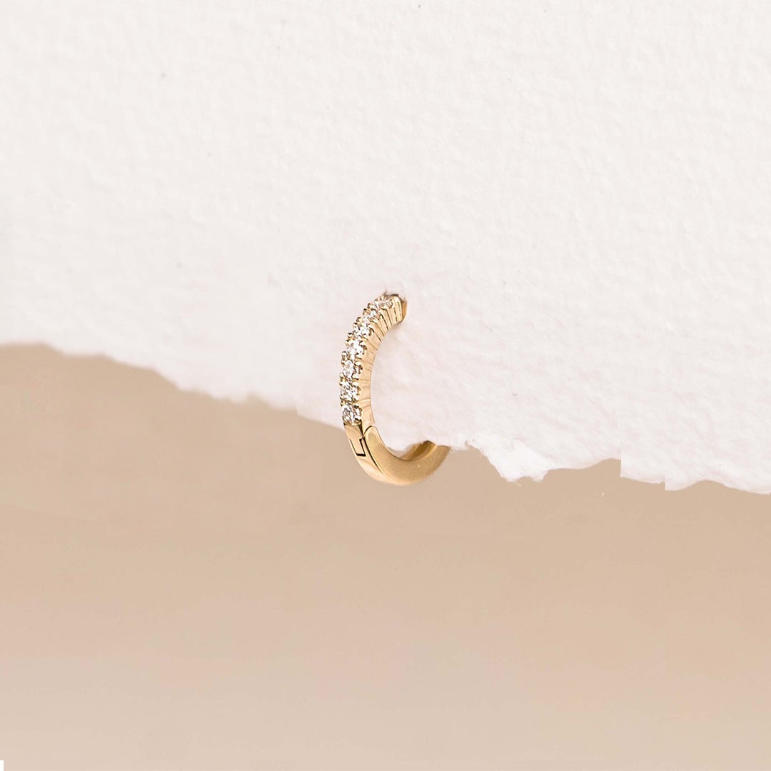 Close-up of 14k Yellow Gold Diamond Huggie Earring - Susanna (Single) with 9 sparkling lab grown diamonds on white background