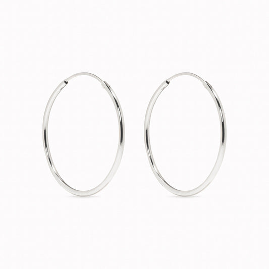 Close-up of White Gold Hoops 25mm - Sonia in sleek 14k white gold on a white background in soft lighting