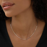 Close-up of a woman wearing the 14k White Gold Petal Chain Necklace - Fleur with a black top and natural lighting
