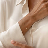 Close-up of a Bezel Set Diamond Bracelet 14k Gold - Vilda worn on a wrist with a cream satin blouse background