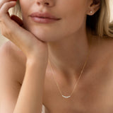 Close-up of woman wearing Graduated Diamond Necklace 14k Gold - Caterina with seven diamonds on a curved gold bar