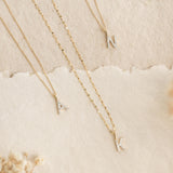 Three 14k gold cable chain necklaces with diamond-studded letter pendants A, K, and N on a neutral background