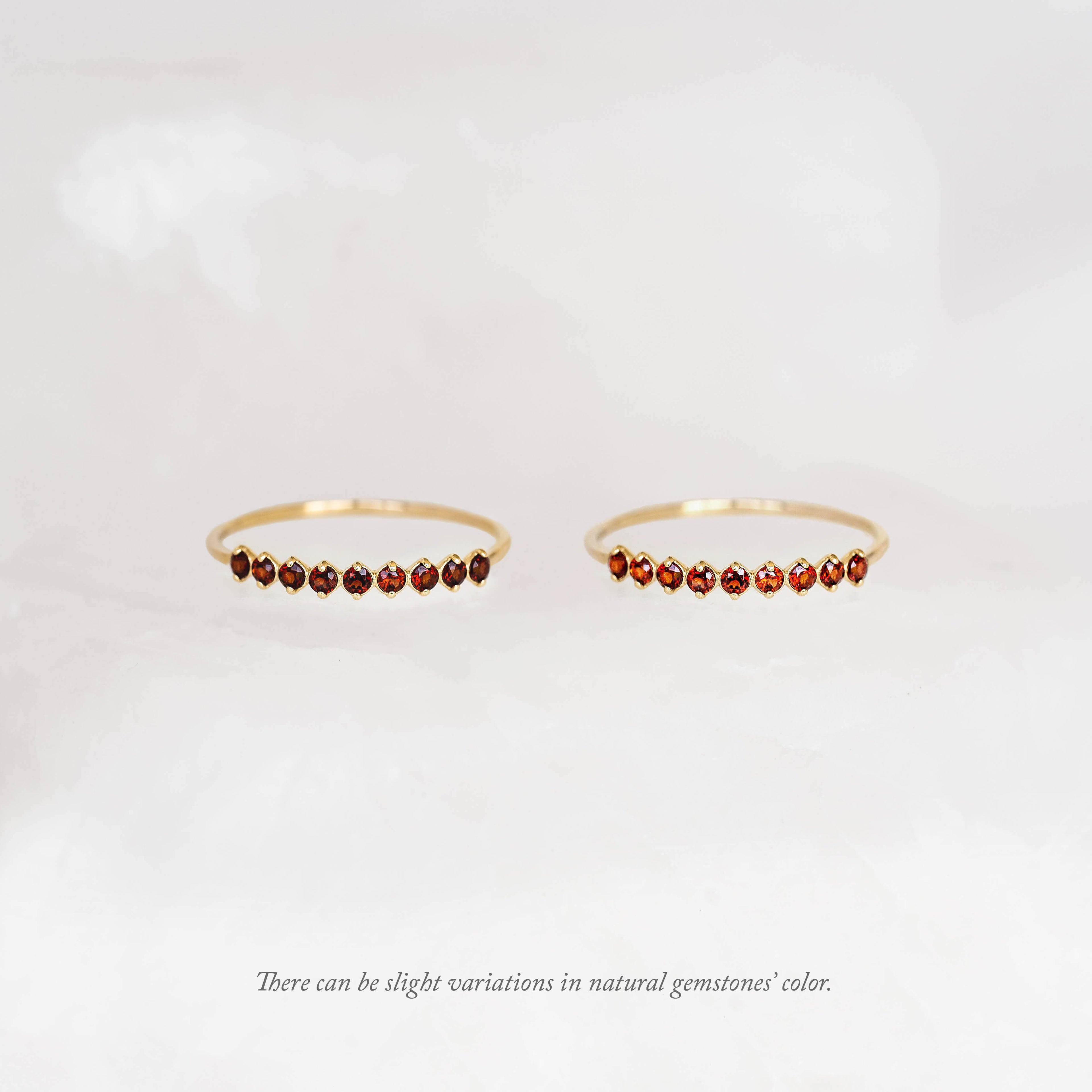 Two Gold pear rings with natural gemstone charms, displayed against a soft cream background.