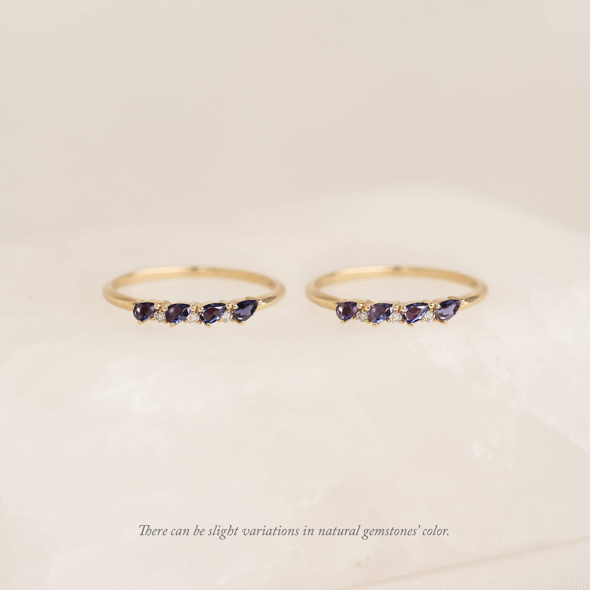 Two Gold pear rings with natural gemstone charms, displayed against a soft cream background.
