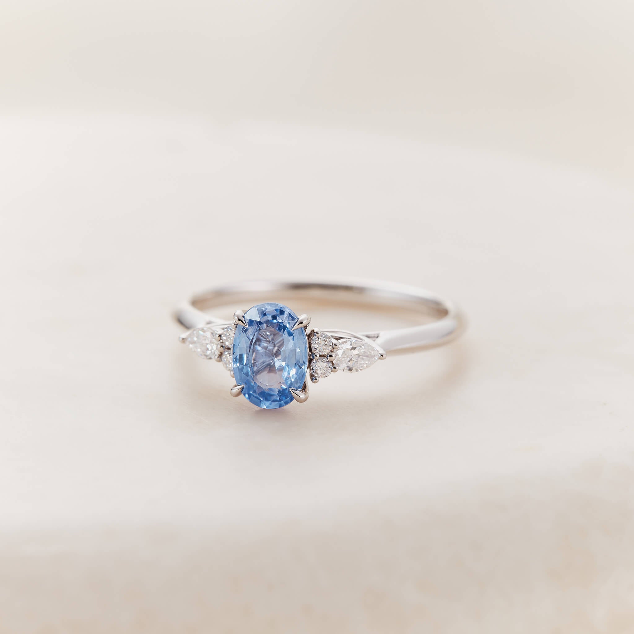 An elegant White Gold ring centered with a vibrant, oval-cut cornflower blue sapphire.