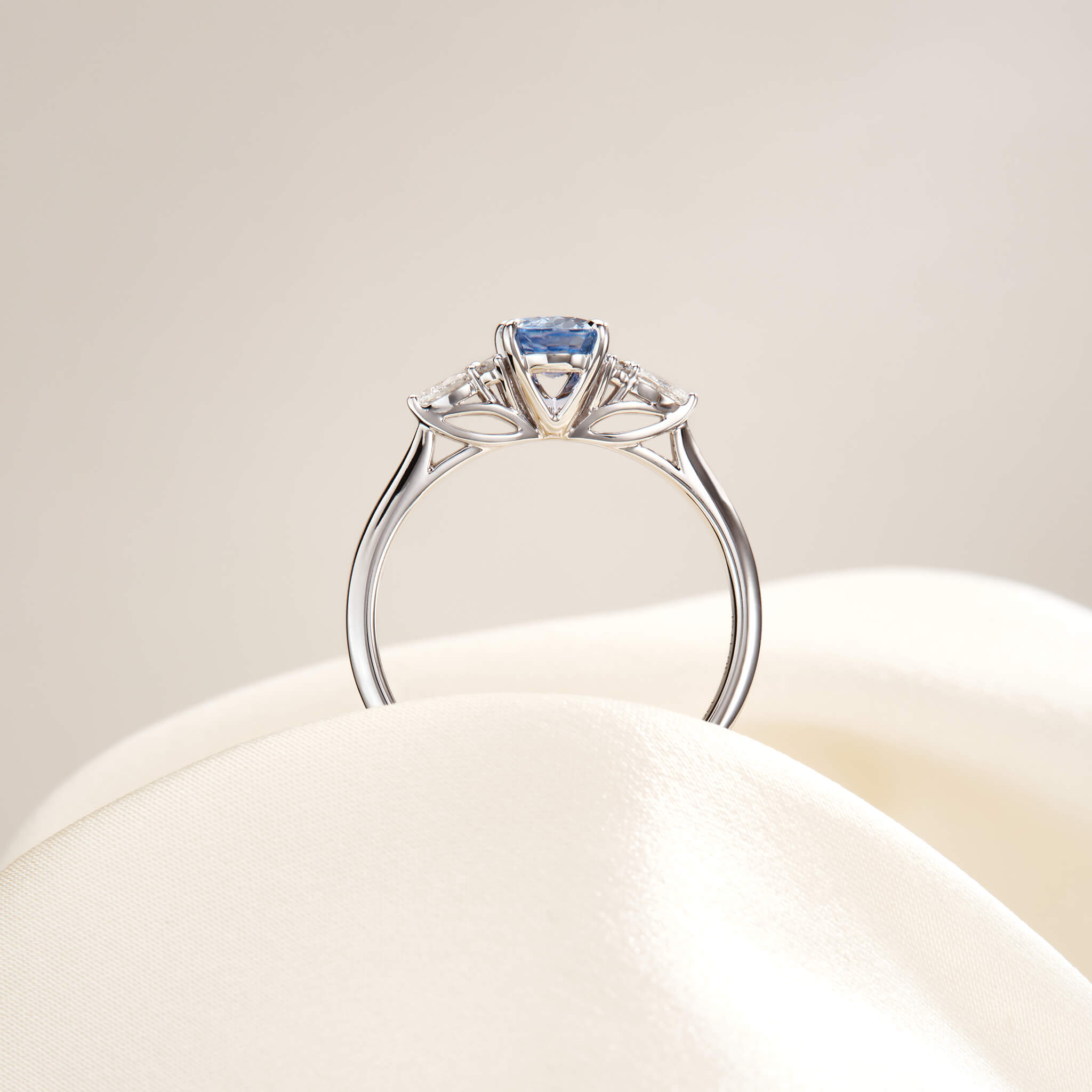 The 14k White Gold ring features a light, icy-blue oval sapphire centerpiece flanked by small cluster diamond accents.
