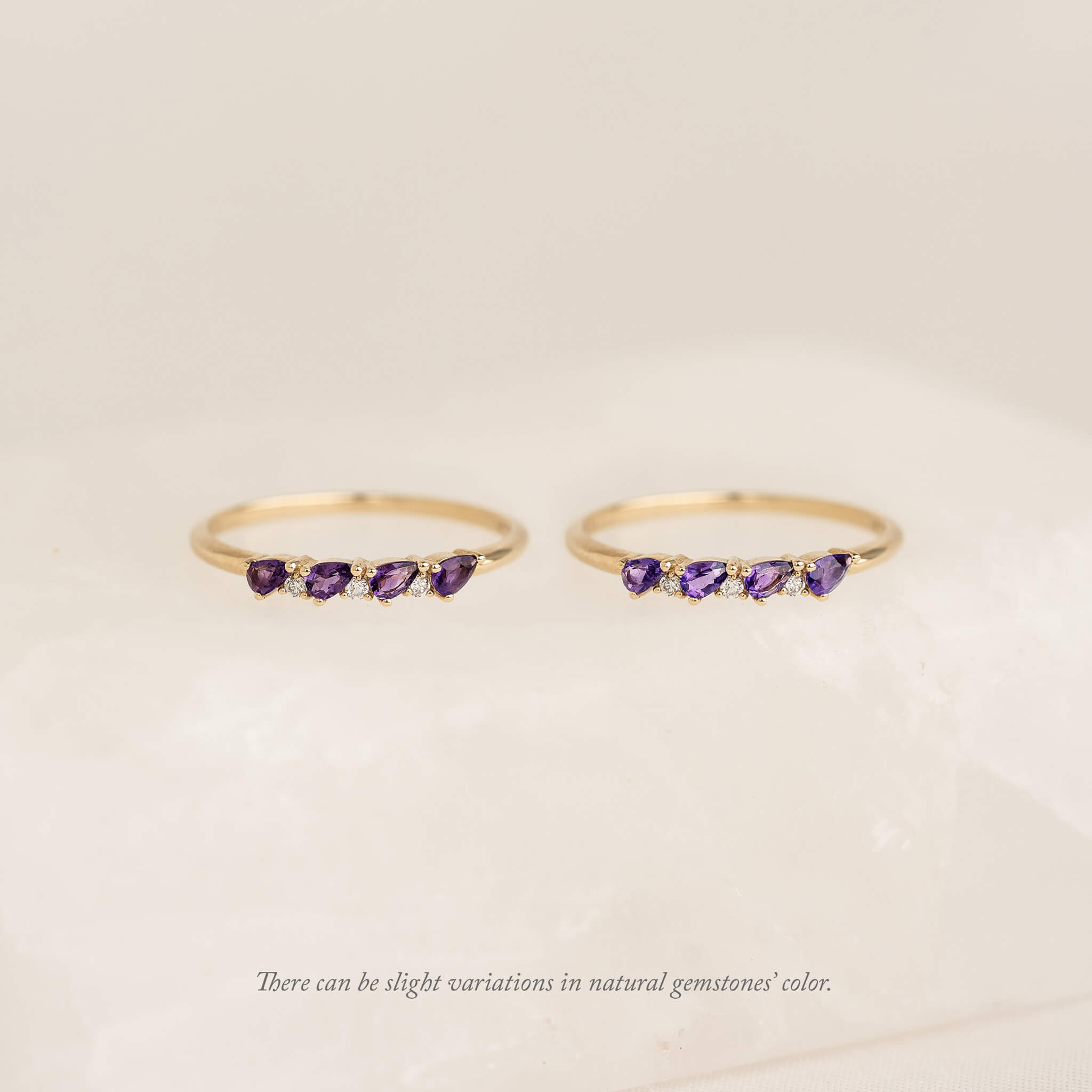 Two Gold pear rings with natural gemstone charms, displayed against a soft cream background.