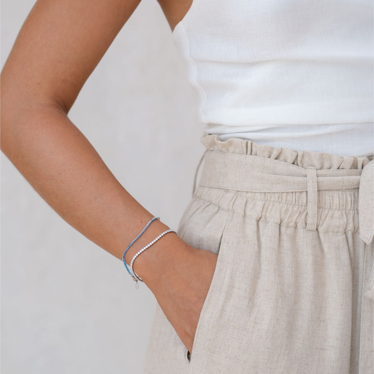 Half tennis bracelet stacked on model with white and blue gemstones