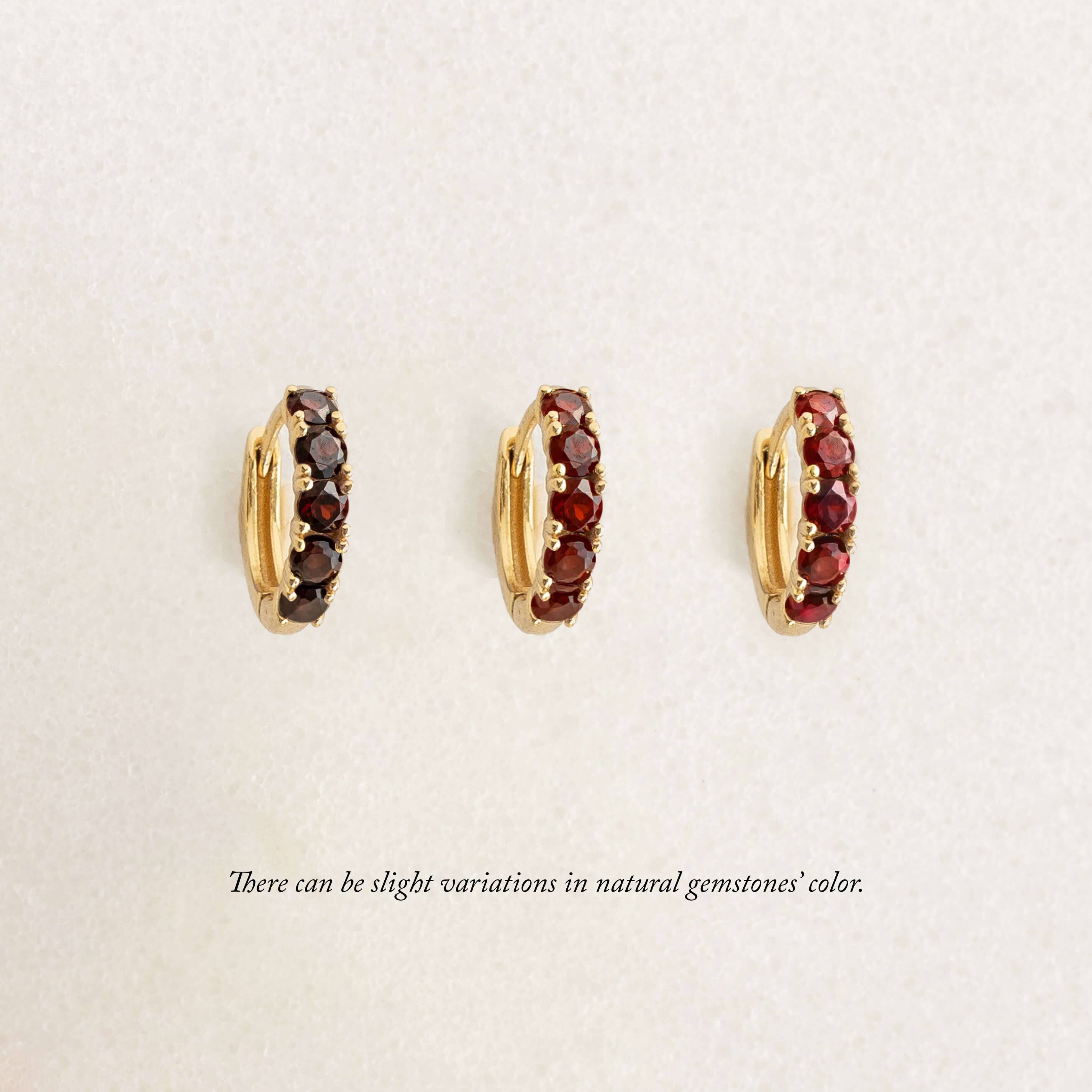 Three Gold hoop earrings, each set with garnet gemstones, set in gold vermeil. Arranged in a row on a light background.