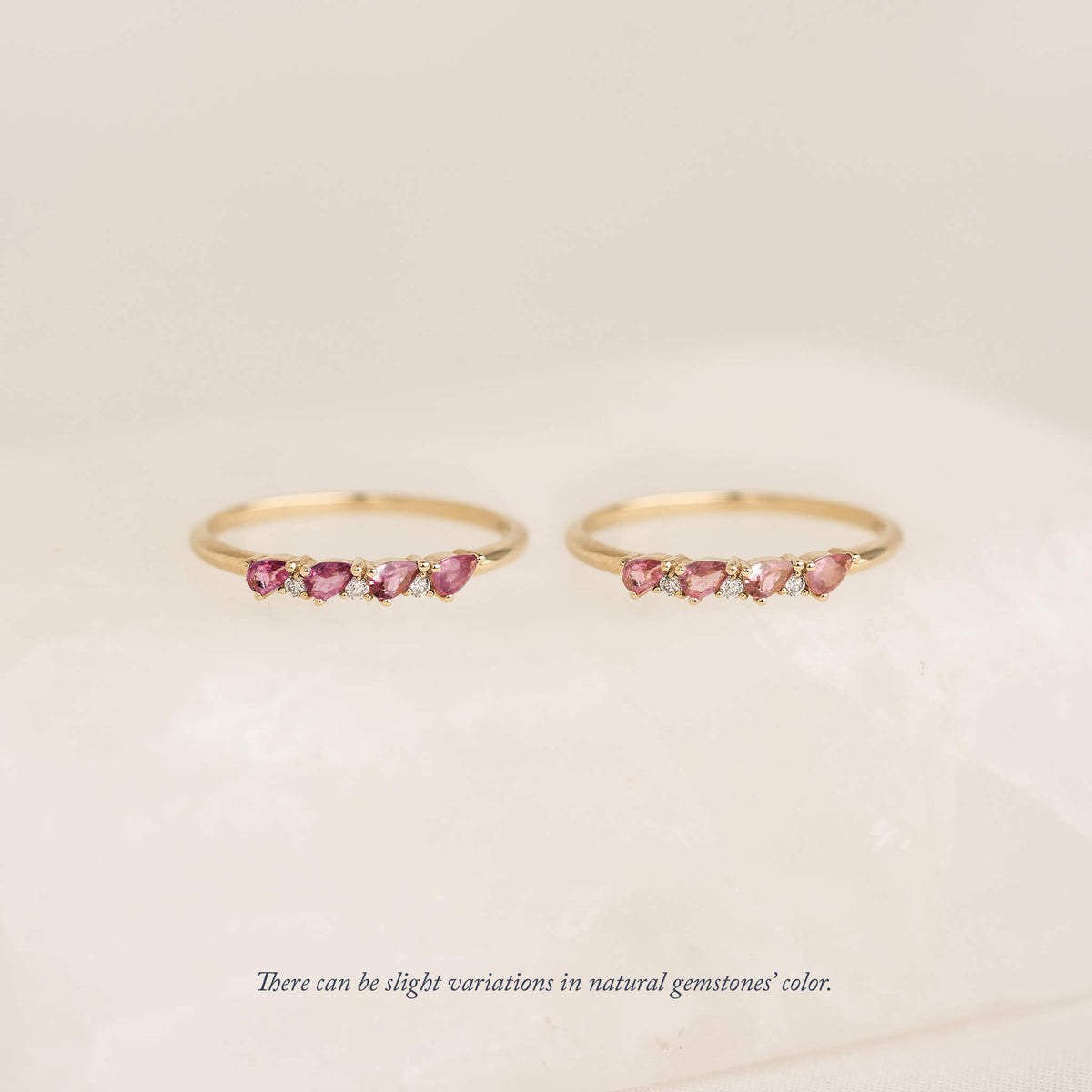 Two Gold pear rings with natural gemstone charms, displayed against a soft cream background.