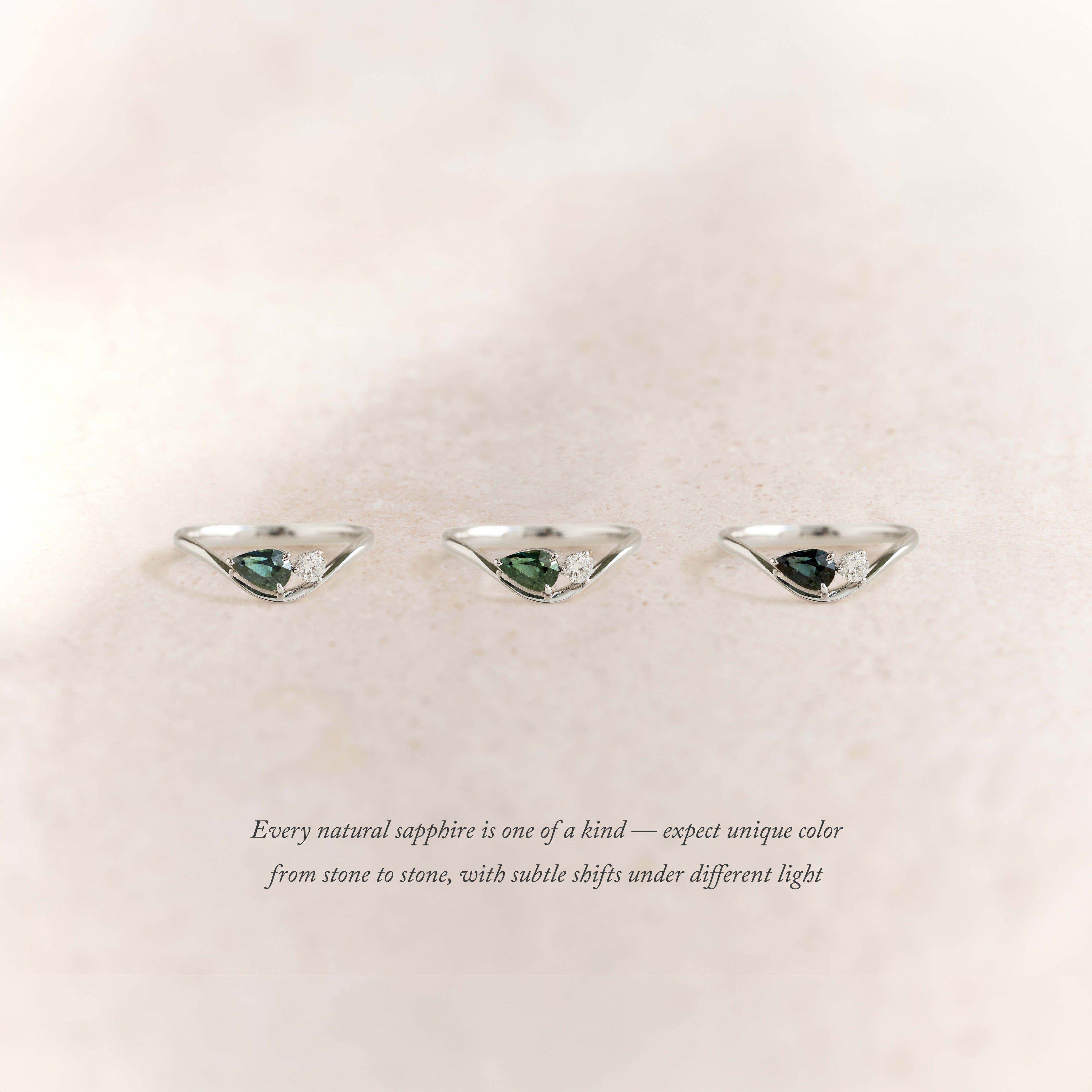 Three White Gold rings arranged horizontally on a soft beige background, each featuring a pear-shaped green sapphire paired with small white accent stones.