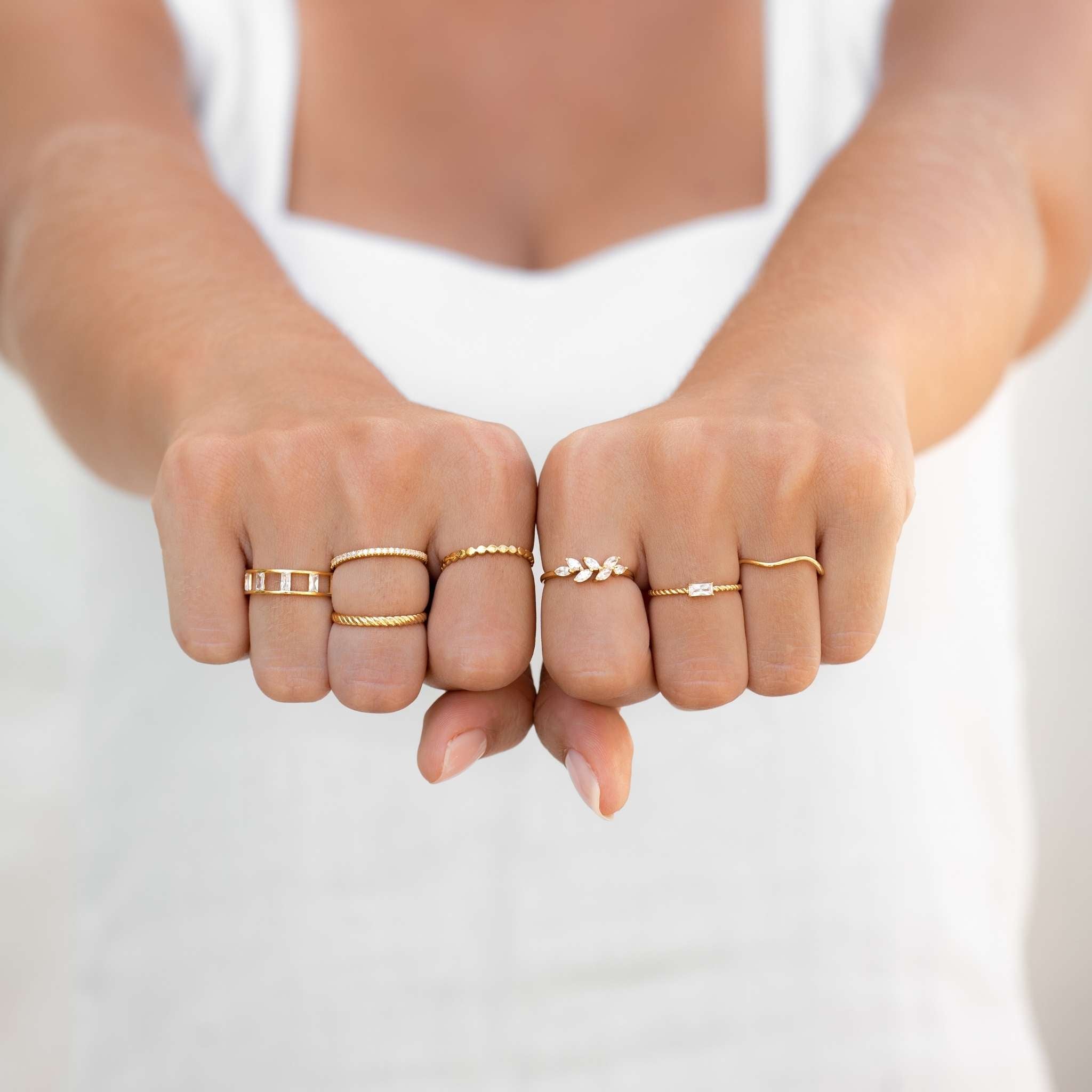 Gold stacking rings on model with textured bands and gemstone rings in gold vermeil