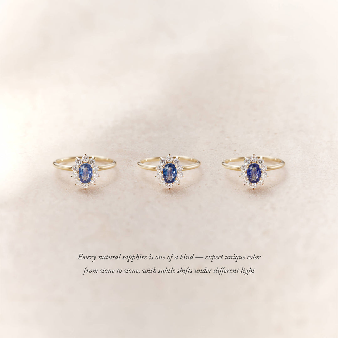 Three Yellow Gold halo rings with oval blue sapphires surrounded by small diamonds are displayed side by side on a soft beige background.
