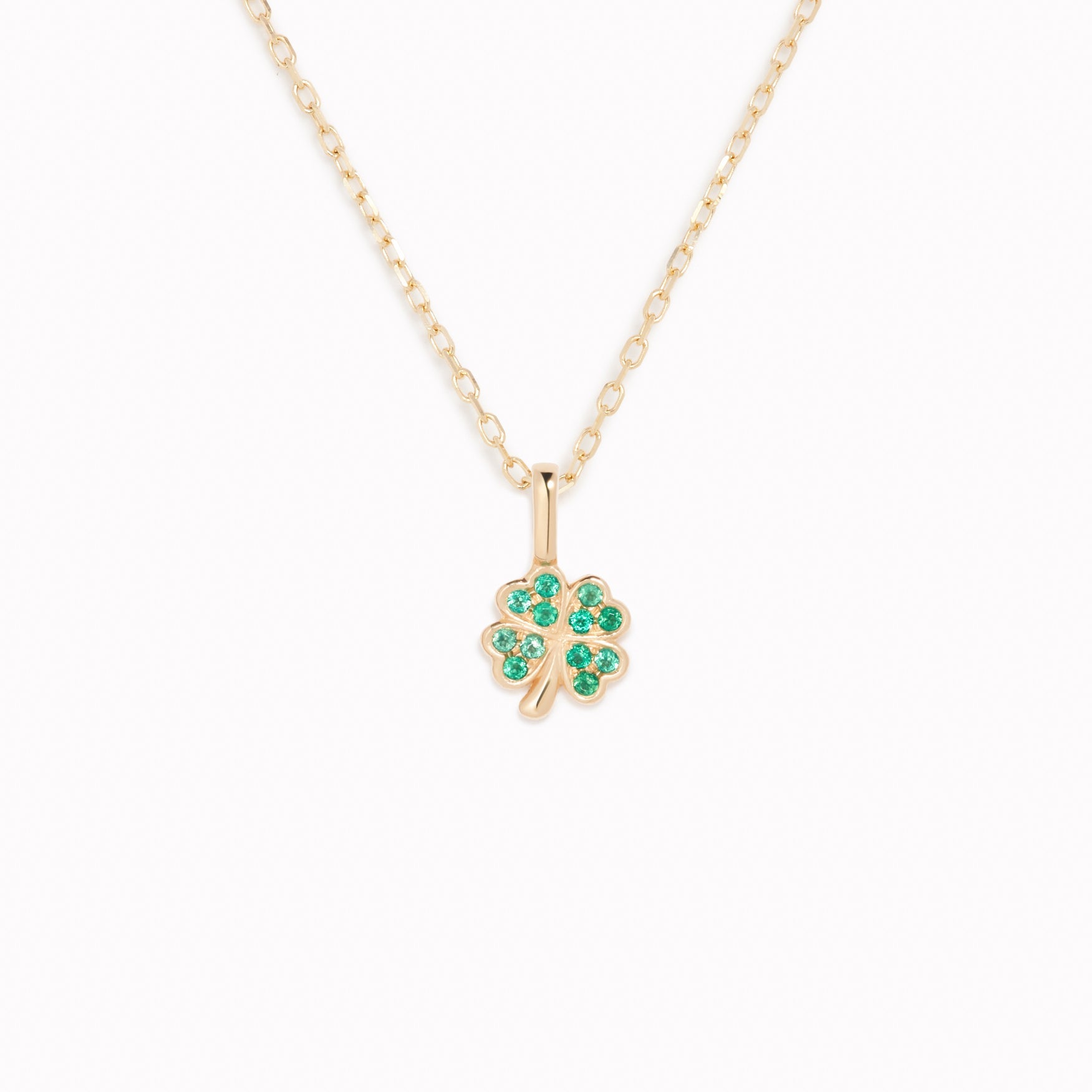 Four Leaf Clover Charm 14k Gold necklace with emerald gemstones on a delicate yellow gold chain on white background