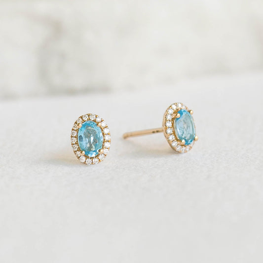 Swiss Blue Topaz Halo Stud Earrings 14k Gold - Marzia with oval blue topaz and diamond halo on white background