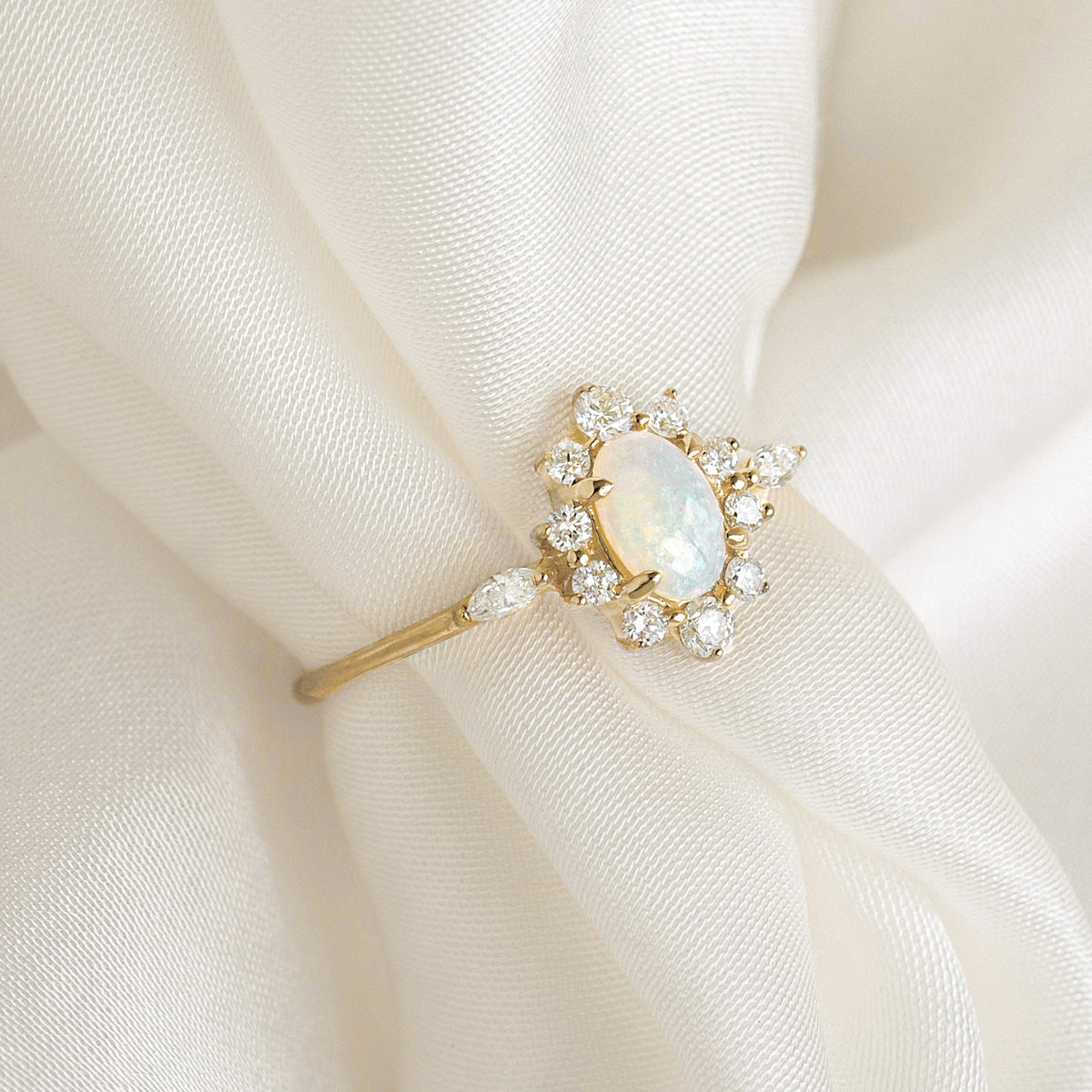 Sunburst Opal Halo Ring - Solana with opal cabochon and diamond halo set in 14k yellow gold on cream fabric background