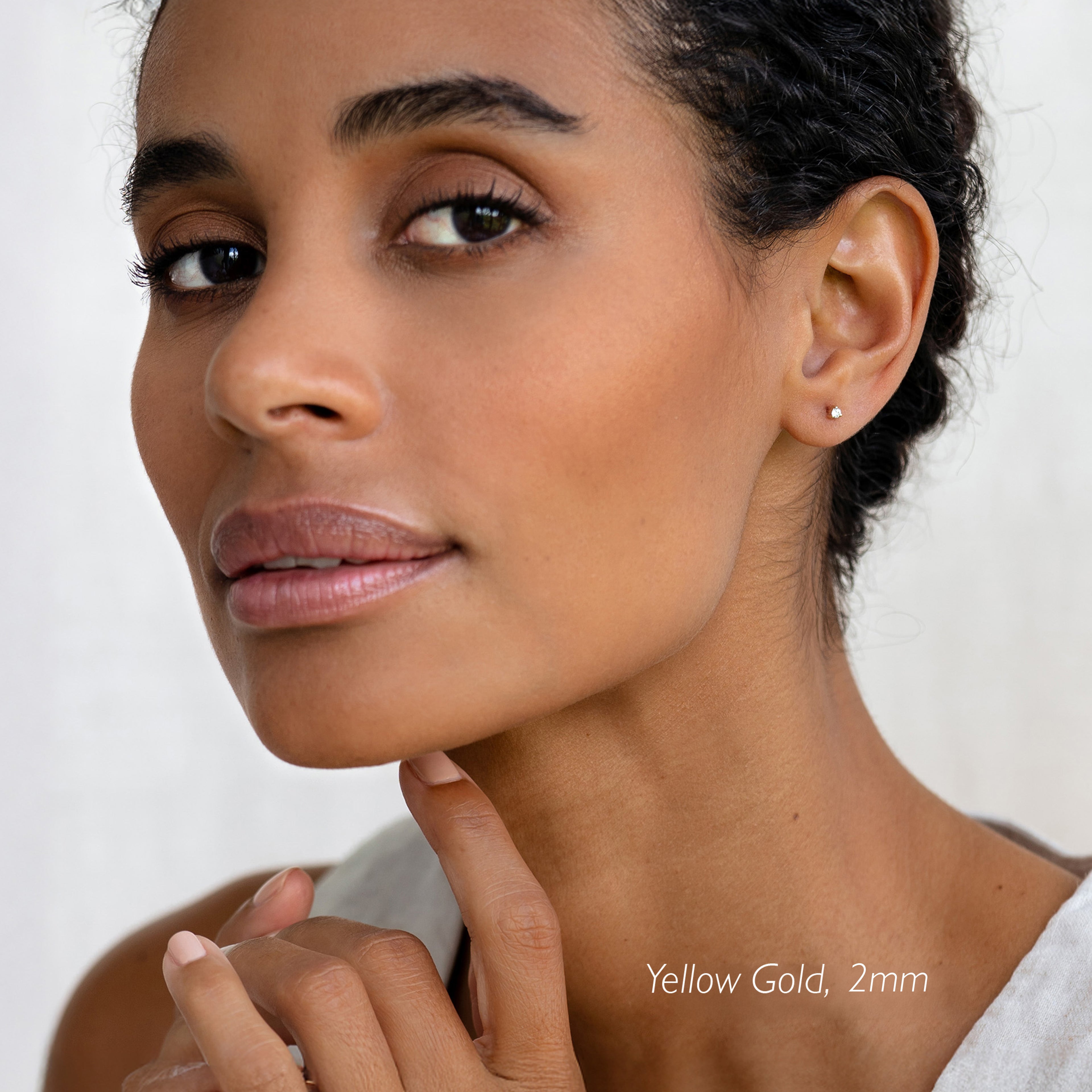 Close-up of a woman wearing 14k White Gold Diamond Stud Earrings 2mm - Aria with natural makeup and soft lighting