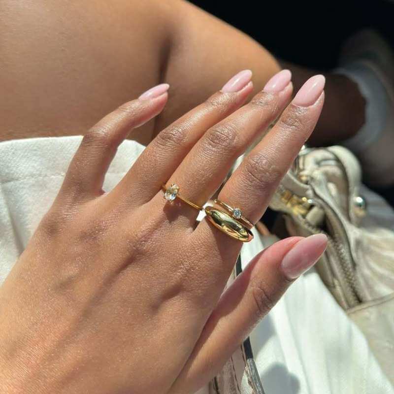 Close-up of a hand with two gold rings on a light background with a blurred shoe in the background