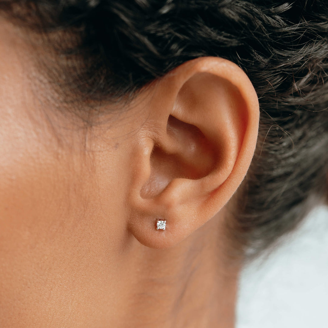 Close-up of an ear wearing 14k White Gold Diamond Stud Earrings 2.5mm - Aria with sparkling lab grown diamond