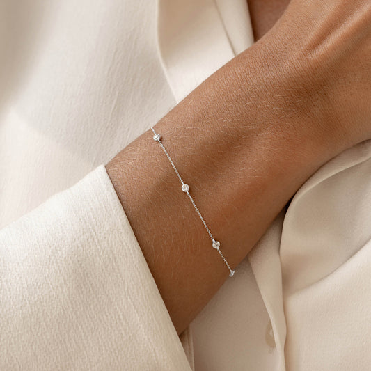 Close-up of Bezel Set Diamond Bracelet 14k White Gold - Vilda worn on wrist over cream fabric background