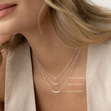 Close-up of a woman wearing the Graduated Diamond Necklace White Gold - Caterina with seven diamonds on a white gold chain