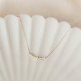 Graduated Diamond Necklace 14k Gold - Caterina with seven diamonds on a delicate curved gold chain on a soft background