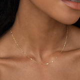 Close-up of a woman wearing the Shimmer Chain Necklace 14k Gold - Clara with a delicate yellow gold mixed link chain