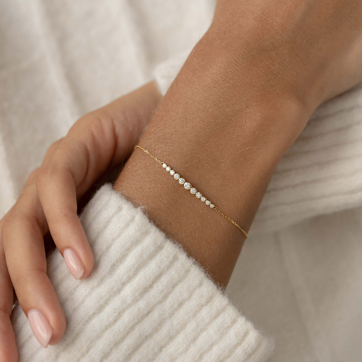Close-up of a wrist wearing Diamond Bracelet 14k Gold - Katla with graduated bezel-set diamonds on delicate gold chain