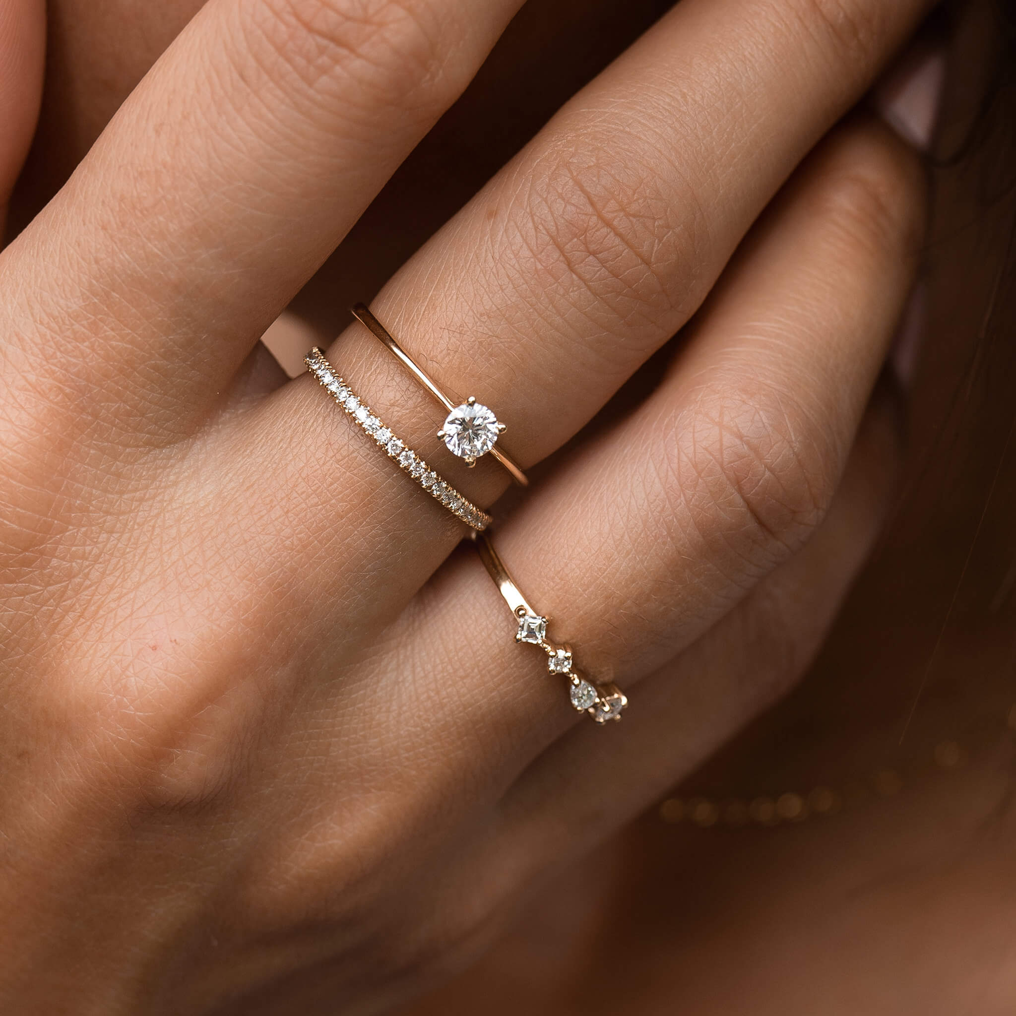 Three lab grown diamond rings on yellow gold bands on model