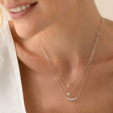 Close-up of a woman wearing the Graduated Diamond Necklace White Gold - Caterina with seven diamonds on a curved white gold bar