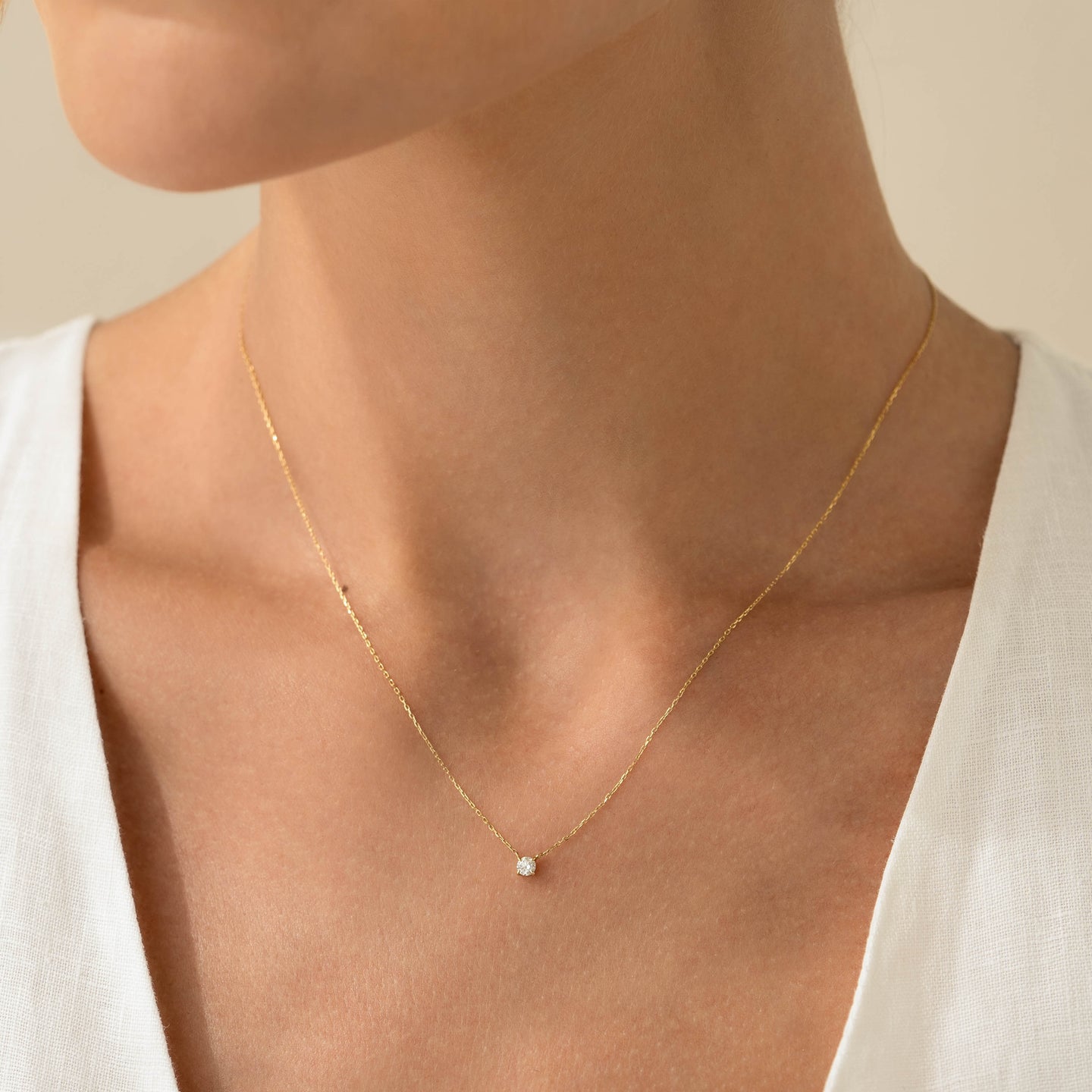 Close-up of a woman wearing the Diamond Pendant Necklace 14k Gold - Johanne with a delicate floating diamond on a gold chain