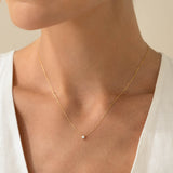 Close-up of a woman wearing the Diamond Pendant Necklace 14k Gold - Johanne with a delicate floating diamond on a gold chain