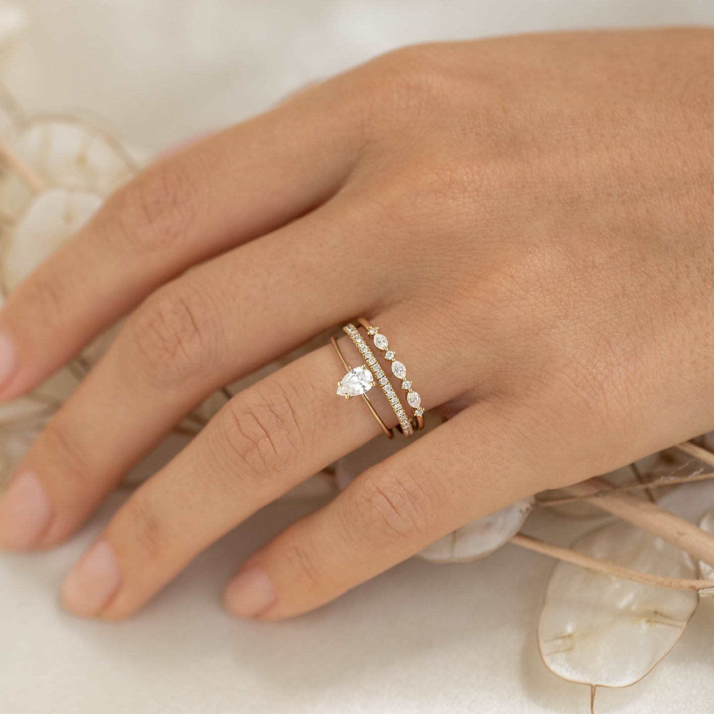 Close-up of hand wearing Marquise and Round Diamond Ring 14k Gold - Nova with stacked delicate gold bands