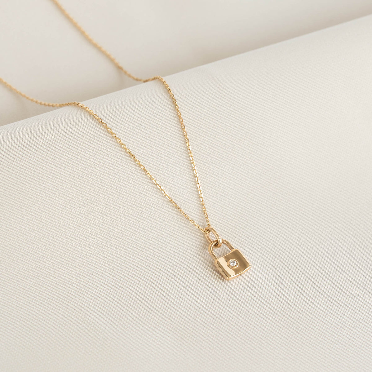 Padlock necklace featuring a faceted heart-shaped pendant displayed on a white textured surface.