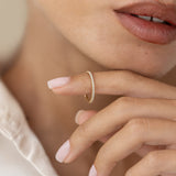 Close-up of a woman holding the Diamond Eternity Ring delicately on her finger against a neutral background