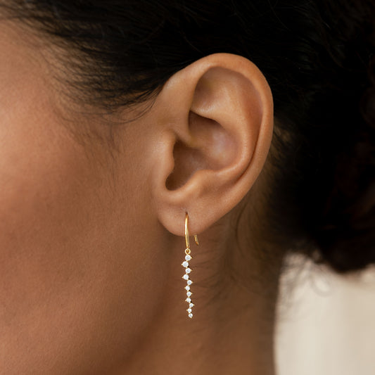 Close-up of an ear wearing Gemstone Drop Earrings - Tamara with graduated cubic zirconia stones set in gold vermeil