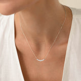 Close-up of a woman wearing the Graduated Diamond Necklace White Gold - Caterina with seven diamonds on a delicate chain