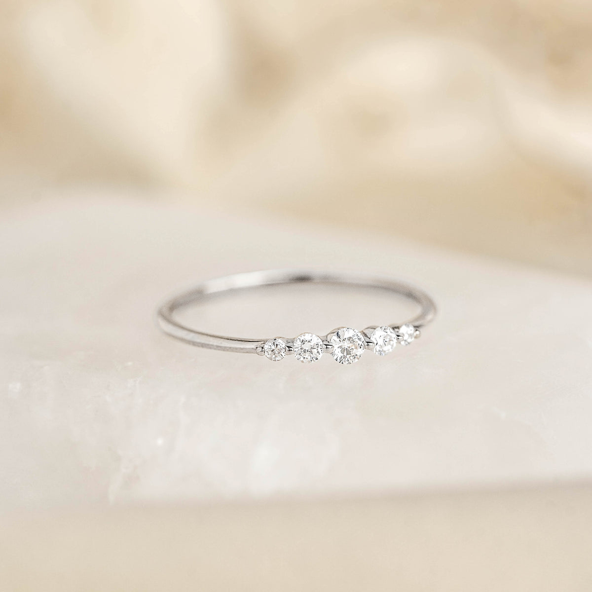 Close-up of Graduated Diamond Ring White Gold - Dahlia featuring five sparkling diamonds on a delicate white gold band