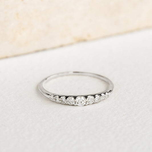 Close-up of Graduated Diamond Ring White Gold - Zoe with nine round diamonds on 14k white gold band on neutral background