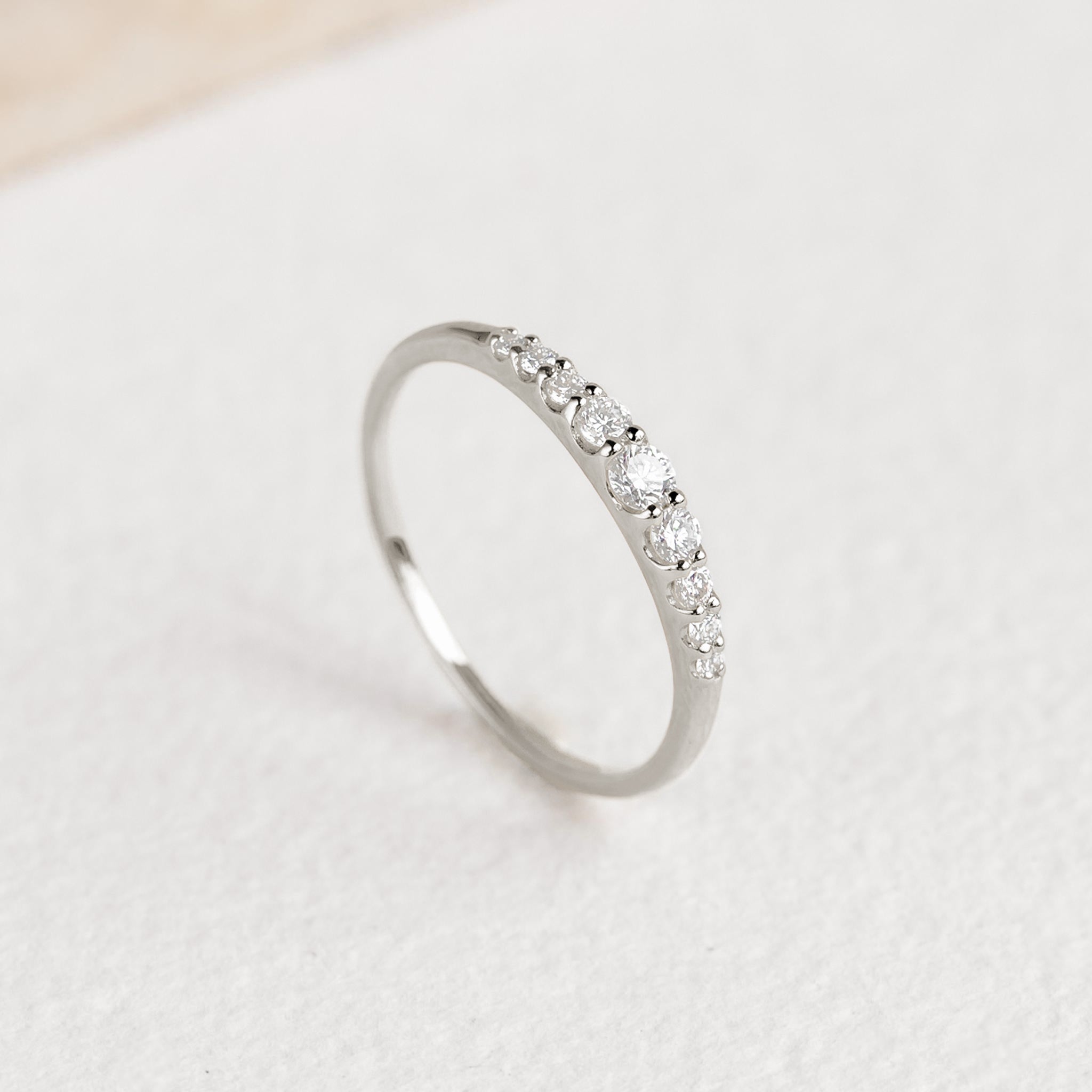 Close-up of Graduated Diamond Ring White Gold - Zoe featuring 9 round diamonds on a sleek white gold band on white surface