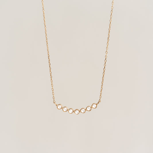 Close-up of June Birthstone Necklace 14k Gold - Mother of Pearl with delicate gold chain on beige background